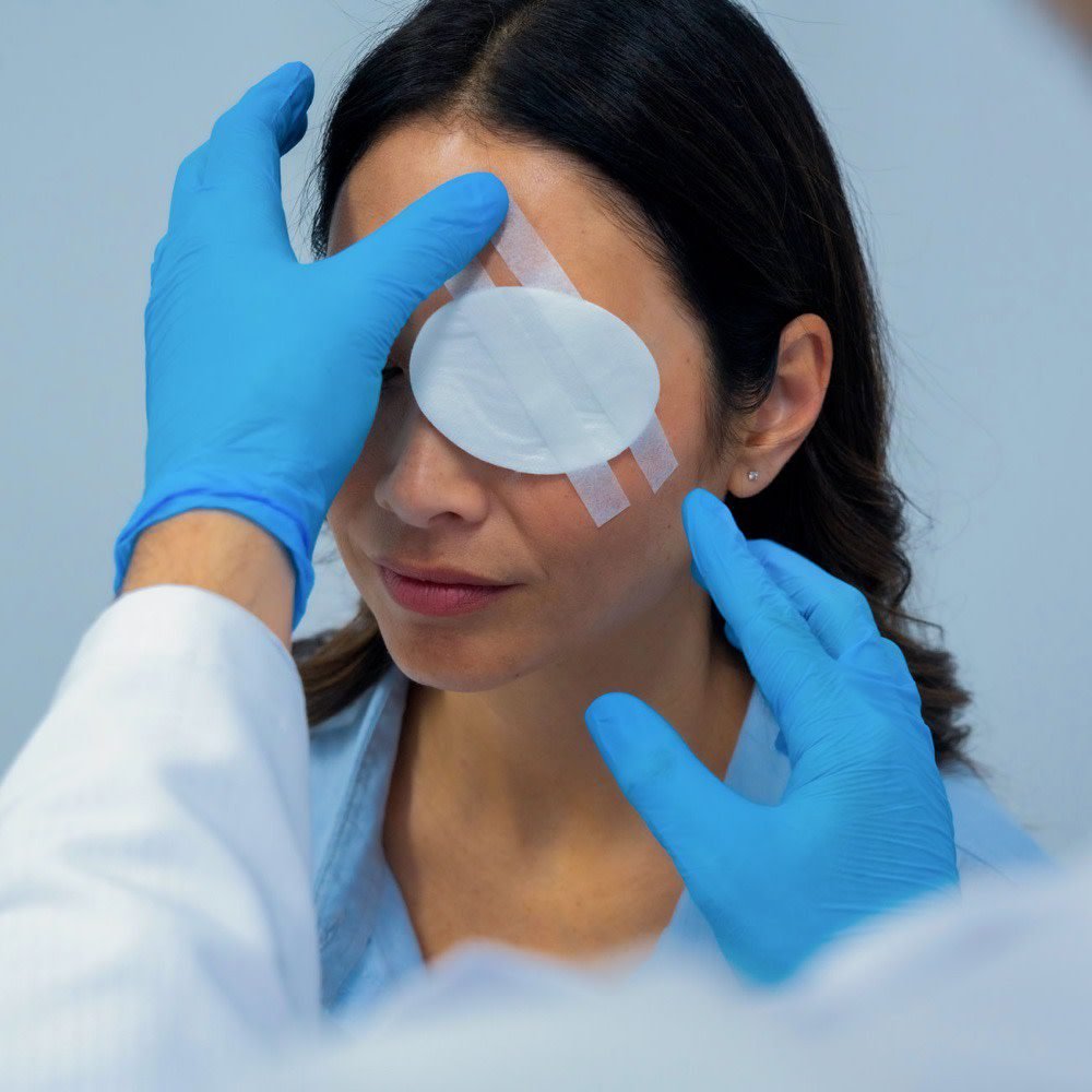 First aider in gloves placing a sterile eye pad over a closed eye